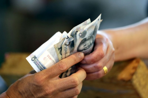 A vendor gives change of 10 yuan notes to a customer at a market in Beijing