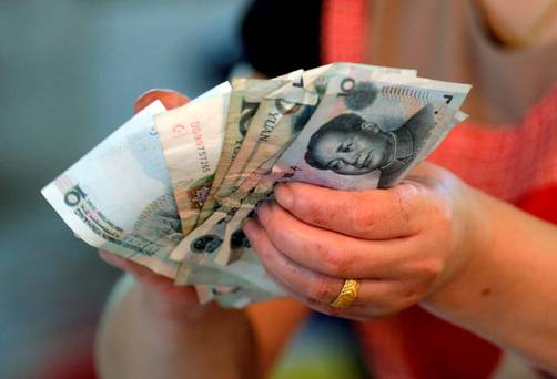 A vendor holds Chinese yuan notes at a market in Beijing