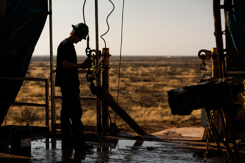 A worker waits to connect a drill bit in the Permian basin outside of Midland Texas