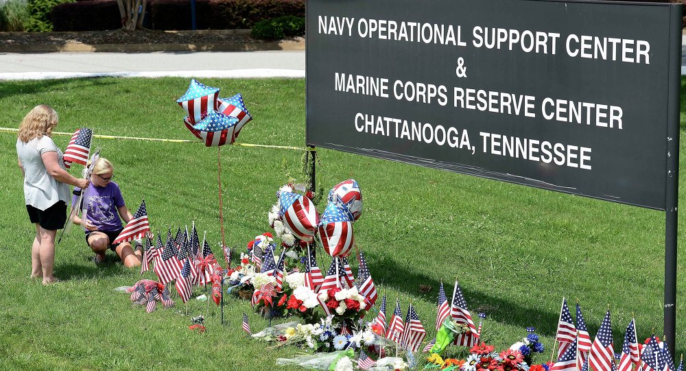 Two women place American flags by a makeshift memorial at the entrance to the Naval Operational Support Center and Marine Reserve Center in Chattanooga Tennessee