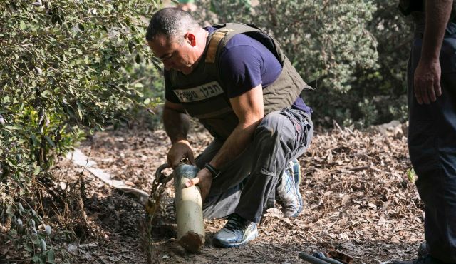 An Israeli police explosives expert holds the remains of a rocket fired from Gaza in Israel's south