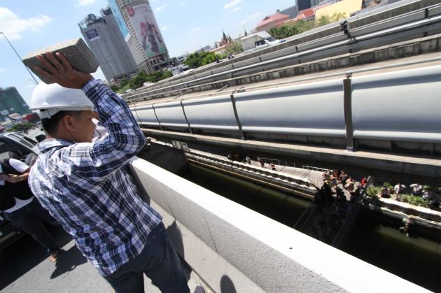 An officer tries to work out where exactly the suspect threw a bomb toward Sathorn Pier by lobbing objects from Taksin Bridge