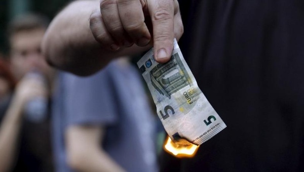 Anti-austerity protesters burn a euro note during a demonstration outside the European Union offices in Athens Greece