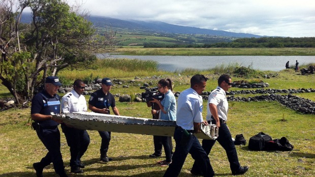 Police carry a piece of debris from an unidentified aircraft found in the coastal area of Saint Andre de la Reunion in the east of the French Indian Ocean island of La Reunion. The two-metre-long piece of wing is speculated to be debris from MH370