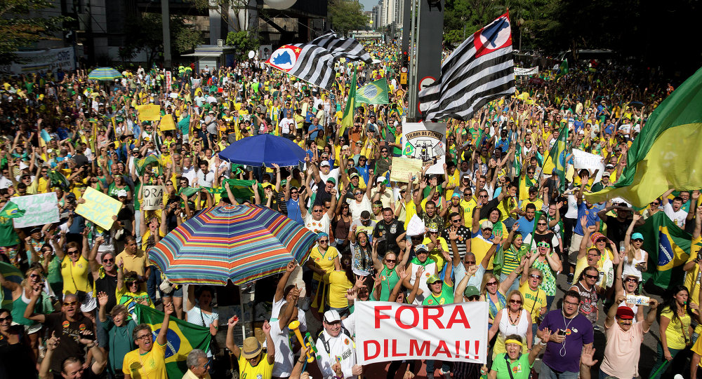 Demonstrators hold a sign that reads in Portuguese Dilma out during a protest demanding the impeachment of Brazil's President Dilma Rousseff in Sao Paulo Brazil