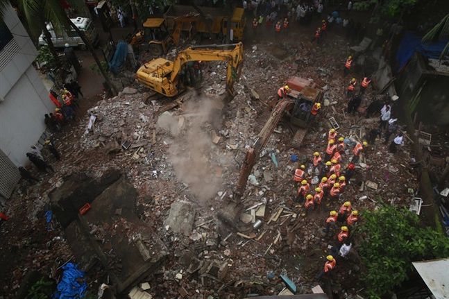 Rescue workers use machinery to clear debris at the site of building collapse in Thane outskirts of Mumbai India Tuesday Aug. 4 2015. According to an official the building was more than 50 years old and had been damaged by the rain.(AP