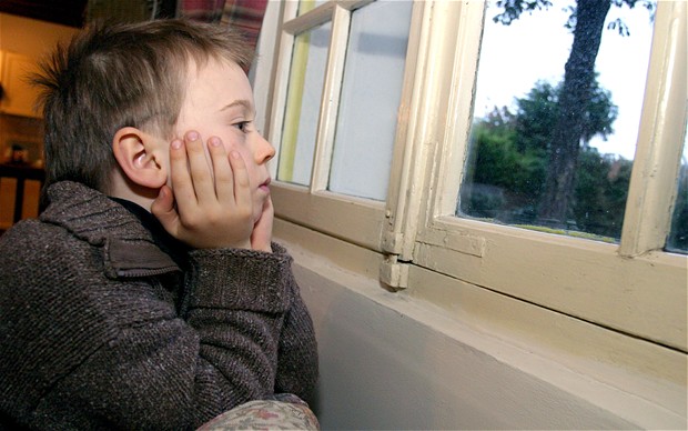 A sad child stares out of the window