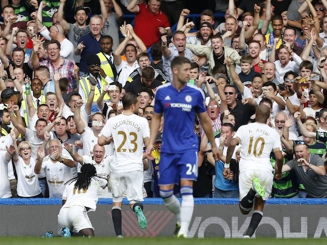 The Swansea City fans celebrate after Swansea City's French striker Bafetimbi Gomis celebrates scoring a second equalising goal from the penalty spot for 2-2 during the English Premier League football match between Chelsea and Swansea City at St