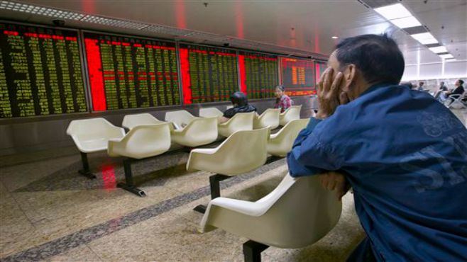 A Chinese investor monitors stock prices at a brokerage house in Beijing Tuesday Aug. 25 2015. China's main stock market index has fallen for a fourth day plunging 7.6 percent to an eight-month low