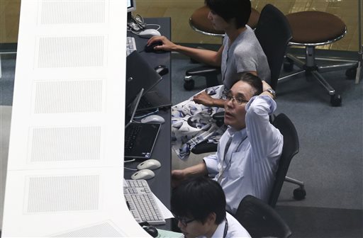 A worker of Tokyo Stock Exchange monitors stock prices on an electric screen during a trading session in Tokyo Monday. Stocks tumbled across Asia on Monday as investors shaken by the sell-off last week on Wall Street unloaded shares in practically every