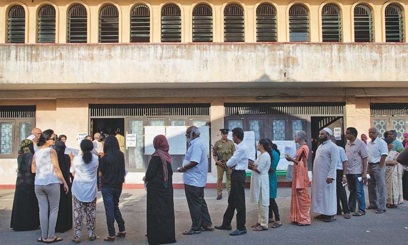 Colombo Voters queue to cast their vote at a polling centre here on Monday.—AP