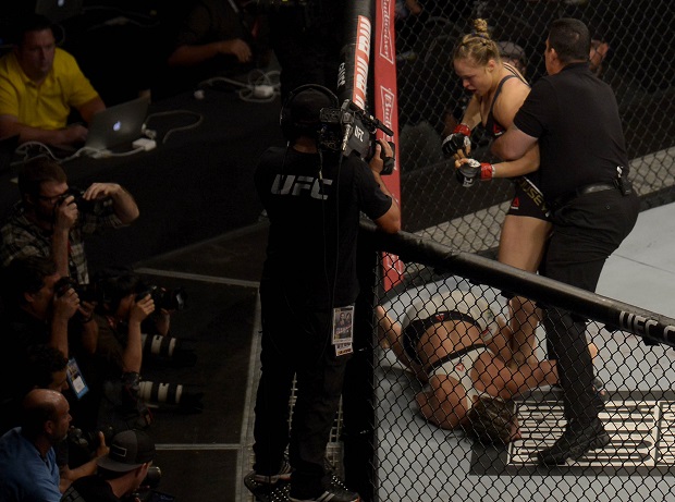 Ronda Rousey center of the United States is pulled away by the referee after she knocked out Brazil's Bethe Correia during their mixed martial arts bantamweight title fight at UFC 190 early Sunday Aug. 2 2015