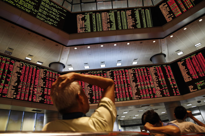 People watch trading boards at a private stock market in Kuala Lumpur Malaysia on Monday