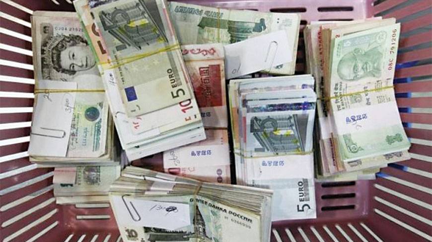 Foreign currency banknotes are placed on a basket for counting during