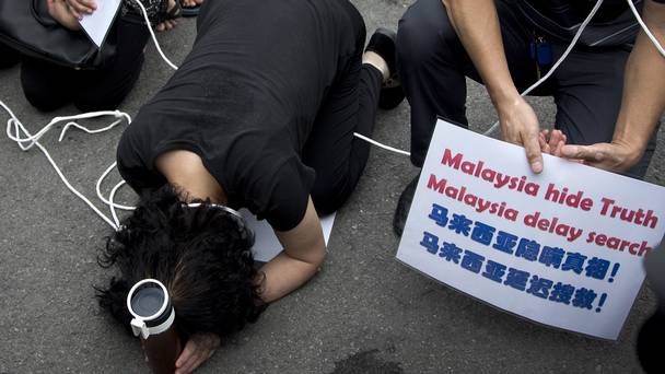 Relatives of the Malaysia Airlines Flight 370 passengers kneel down in front of the media ahead of a briefing given by the airlines outside a help centre in Beijing