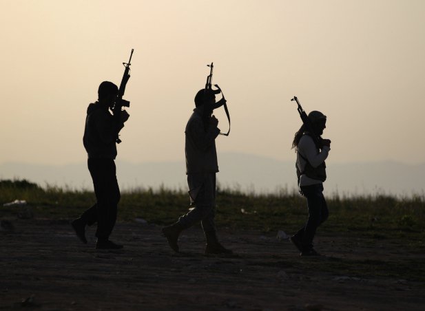 Free Syrian Army fighters carry their weapons as they walk on a frontline in Mork town