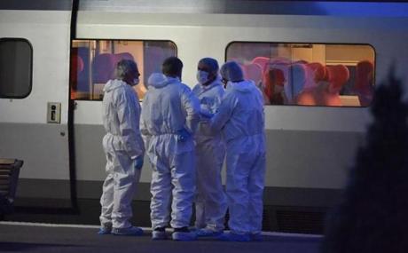 Police in protective suits stand on a platform next to a Thalys train of French national railway operator SNCF at the main train station in Arras northern France