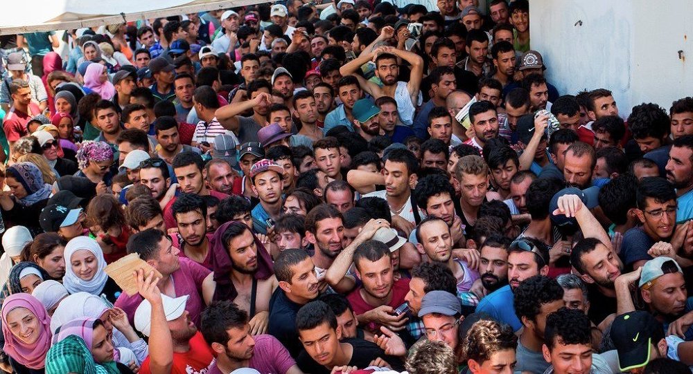 Syrian migrants and refugees gather at a makeshift migrant detention center at Kos abandoned football stadium after crossing from Turkey at the southeastern island of Kos Greece Wednesday Aug. 12 2015