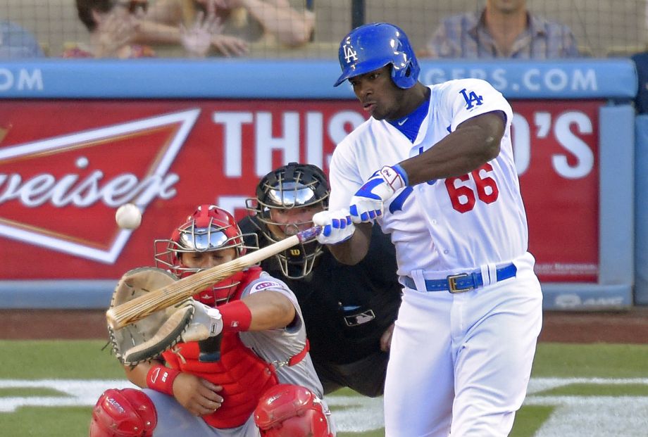 Los Angeles Dodgers Yasiel Puig right hits a solo home run as Cincinnati Reds catcher Brayan Pena left and home plate umpire Dana De Muth watch during the second inning of a baseball game Saturday Aug. 15 2015 in Los Angeles