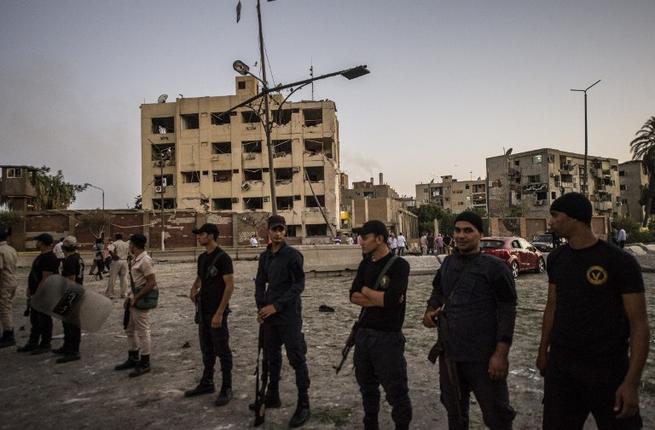 Egyptian riot policemen stand in front of the damaged national security building in northern Cairo's district of Shubra