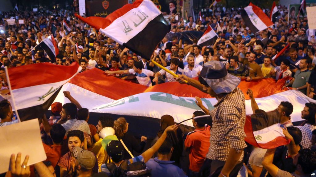 Demonstrators chant in support of Iraqi Prime Minister Haidar al Abadi as they wave national flags during a demonstration at Tahrir Square in Baghdad Iraq