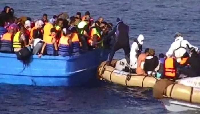 Italian navy personnel pull migrants from a boat in the Mediterranean Sea