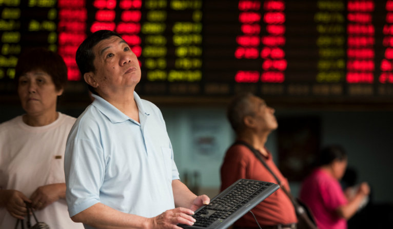 Investors monitor screens showing stock market movements at a brokerage house in Shanghai on Thursday. China has set a lower value for its yuan currency for the third straight day