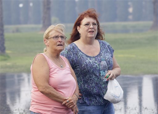 Kim Korth right co-owner of Korth's Pirate's accompanied by her friend Tracy Holcombe watch as firefighters battle to save her mobile home,Thursday