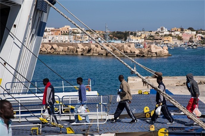 Migrant men board a ship bound for Sicily