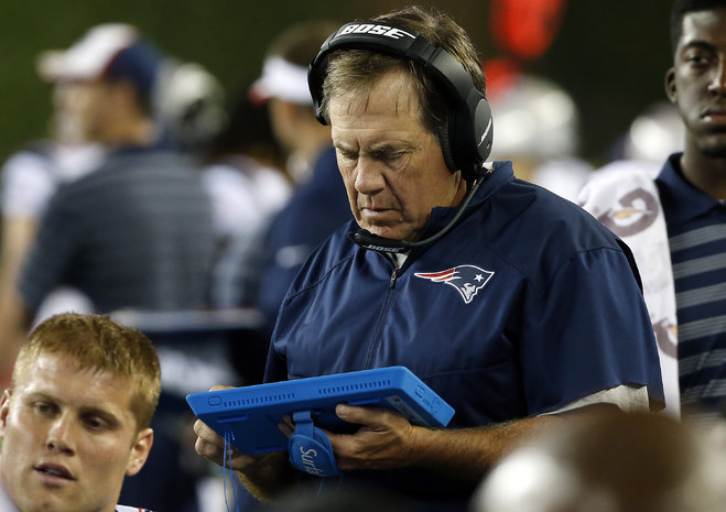 New England Patriots head coach Bill Belichick studies a tablet device on the sideline in the first half of an NFL preseason football game against the Philadelphia Eagles in Foxborough Mass. Coaches players and