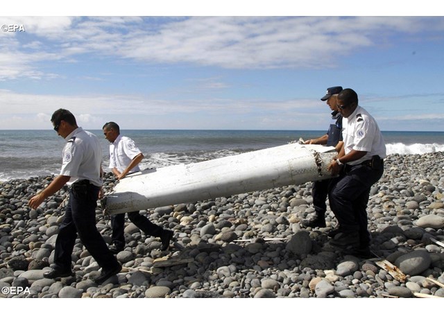 Officers on Reunion Island carry a flap from a Boeing 777 being sent to France for analysis- EPA