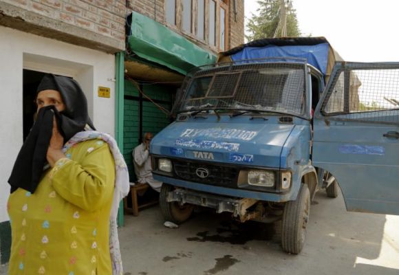 A Kashmiri woman walks near a police vehicle