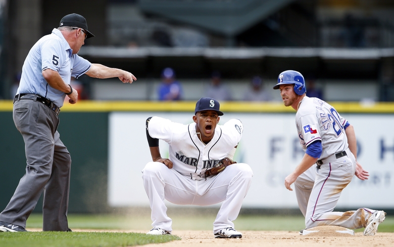 Ketel Marte center reacts after missing a double play against Texas Rangers Ryan Strausborger right during the fifth inning of a baseball game Saturday Aug. 8 2015 in Seattle. Second base umpire Dale Scott left