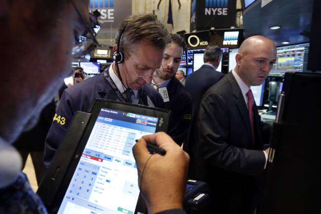 Specialist Jay Woods right works with traders at his post on the floor of the New York Stock Exchange