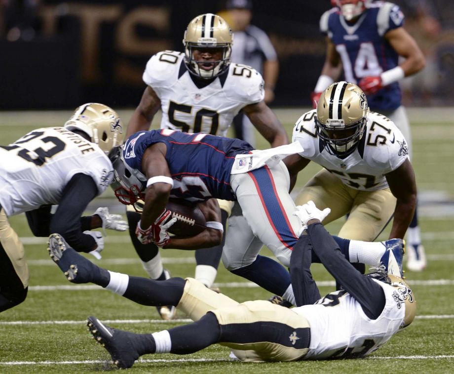 New England Patriots running back Dion Lewis is upended between New Orleans Saints cornerback Stanley Jean Baptiste and inside linebacker David Hawthorne in the first half of a preseason NFL football game in New Orleans Saturday Aug. 22