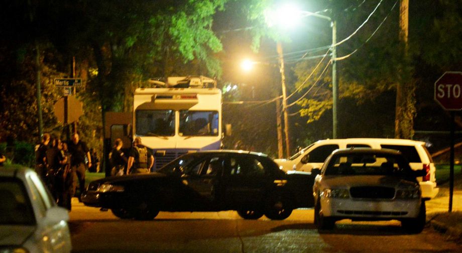 Law enforcement officials surround the scene where a Shreveport police officer was shot Wednesday Aug. 5 2015 in Shreveport La. Police in northwest Louisiana say an officer has died after being shot while on duty and a manhunt for a suspect is under