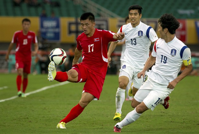 North Korea's So Hyon Uk left kicks the ball away from South Korea's Lee Ju-yong center and Kim Young-gwon right during their East Asian Cup soccer match in Wuhan in central China's Hubei Province Sunday Aug. 9 2015. The match ended in a 0-0 draw