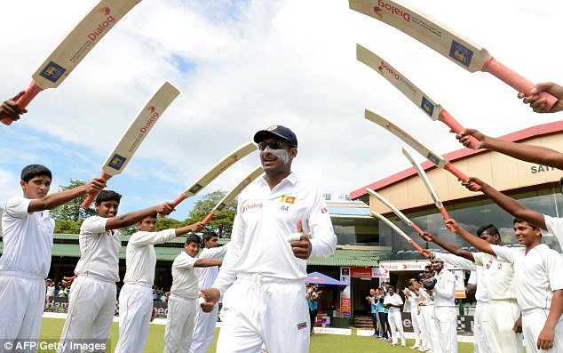 Sri Lankan cricketer Kumar Sangakkara walks through an'archway of cricket bats ahead of his final Test