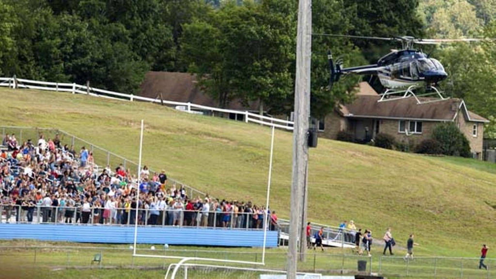 A West Virginia State Police helicopter lands on the football field at Philip Barbour High School in Philippi W.V. where students wait on the football field bleachers