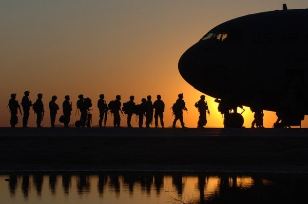 'military male and female soldiers getting on a plane