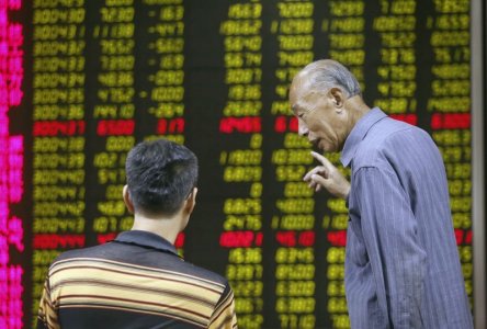 Investors talk in front of an electronic board showing stock information at a brokerage house in Beijing China