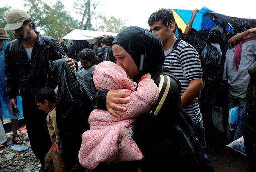 A migrant holds a child under the rain close to the border crossing between Greece and Macedonia near the village of Idomeni Greece