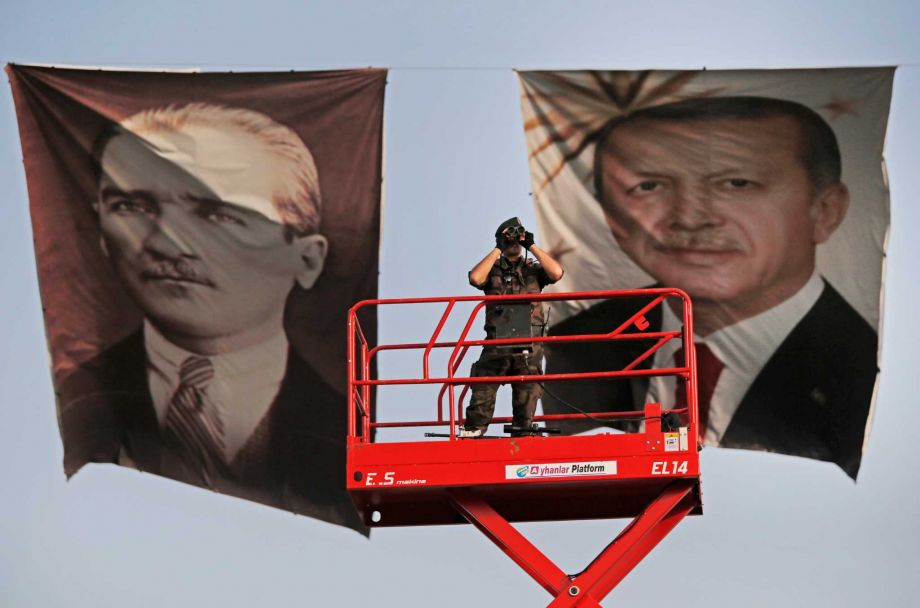 Turkish police officer scans the area from a platform backdropped by posters of Turkish Republic founder Mustafa Kemal Ataturk left and Turkey's current President Recep Tayyip Erdogan right during