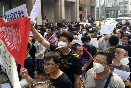 Residents some wearing masks hold banners and placards as they stage a protest outside a hotel where officials held daily media conferences in northeastern China's Tianjin municipality Monday Aug. 17 2015. About a hundred people whose residences