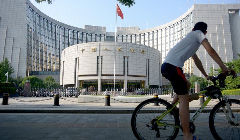 WANG ZHAO  sA man rides his bicycle past the People's Bank of China in Beijing