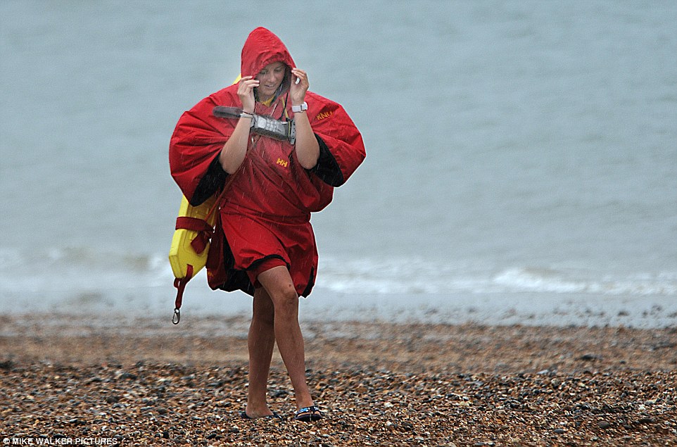 Heavy showers are sweeping across the UK as some areas of the country experience nearly an inch of rain in just 12 hours. Above a lifeguard patrols the beach at Southsea Hampshire