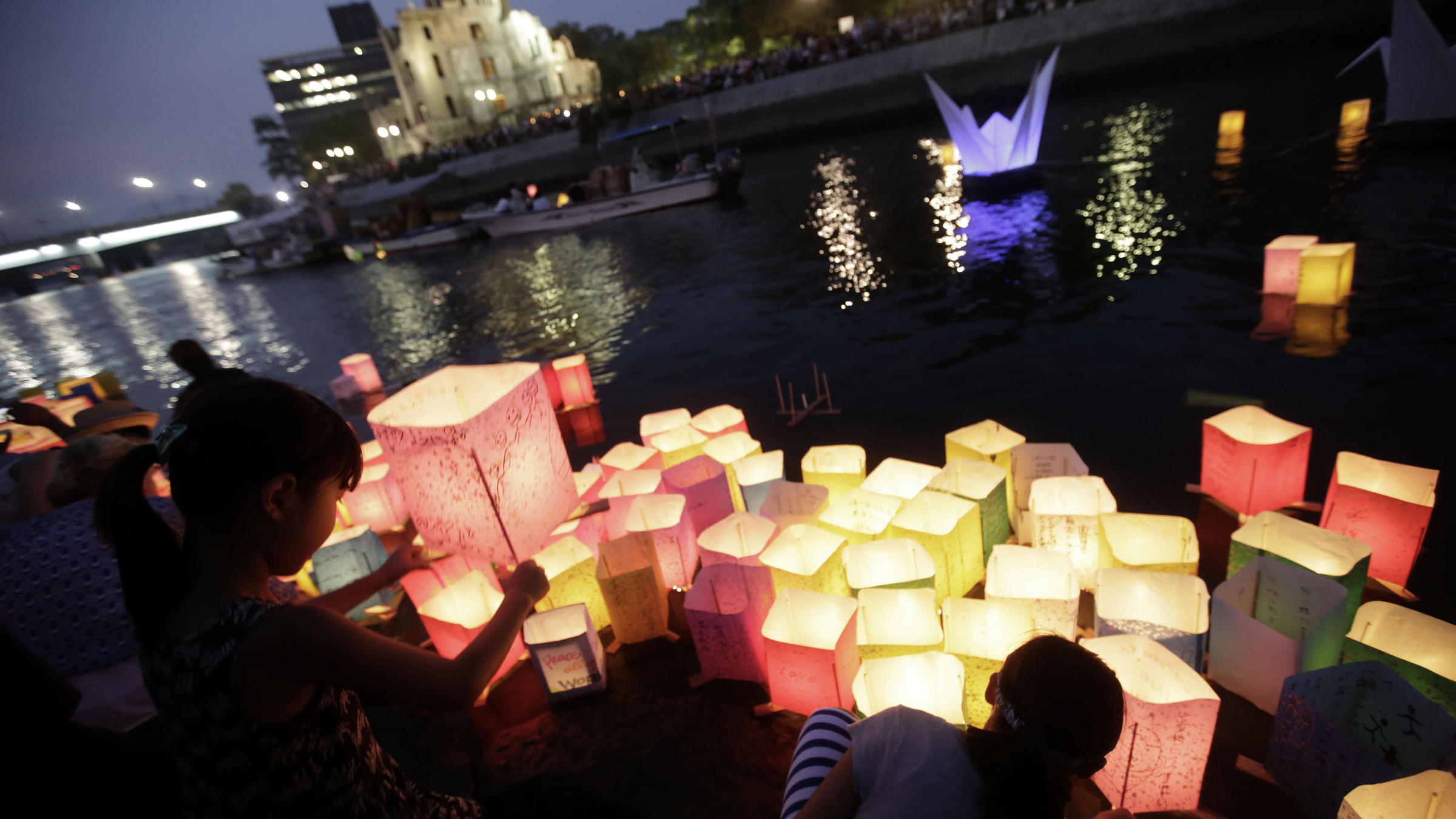 Children offer prayers as after releasing paper lanterns to the Motoyasu River where tens of thousands of atomic bombing victims died with the backdrop of the Atomic Bomb Dome in Hiroshima on Thursday