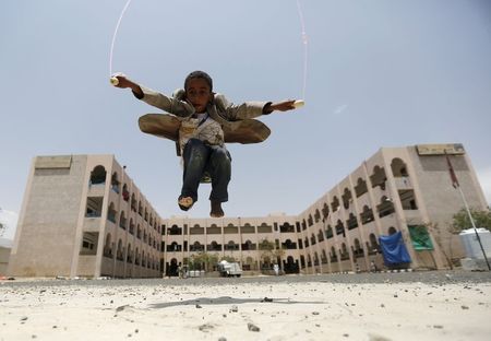 People seek cover from rising dust as a Qatari military cargo plane carrying aid lands at the international airport of Yemen's southern port city of Aden