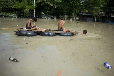 Flood-affected residents use a make-shift raft to travel through floodwaters in Kalay upper Myanmar's Sagaing region