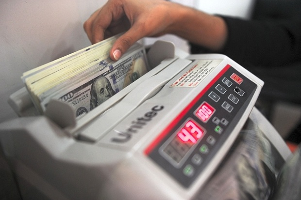 A currency exchange clerk counts US dollar notes for customers in Ampang Malaysia